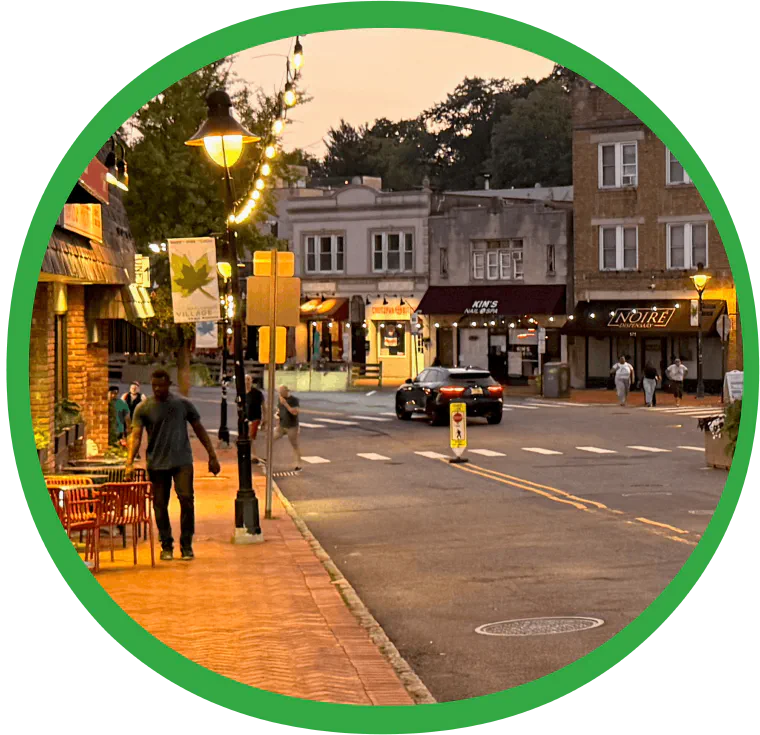 An evening view of the village centre in Maplewood, with cafe tables and string lights along the sidewalk.