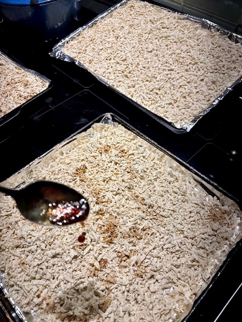 Three sheetpans loaded with grated tofu in an oven